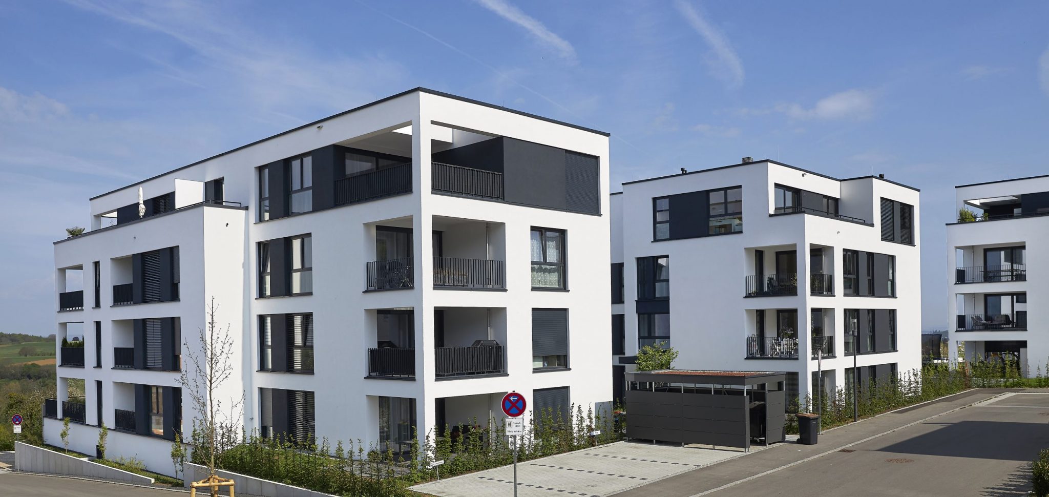 Moderne Mehrfamilienhäuser mit Balkonen und begrünten Außenanlagen.
