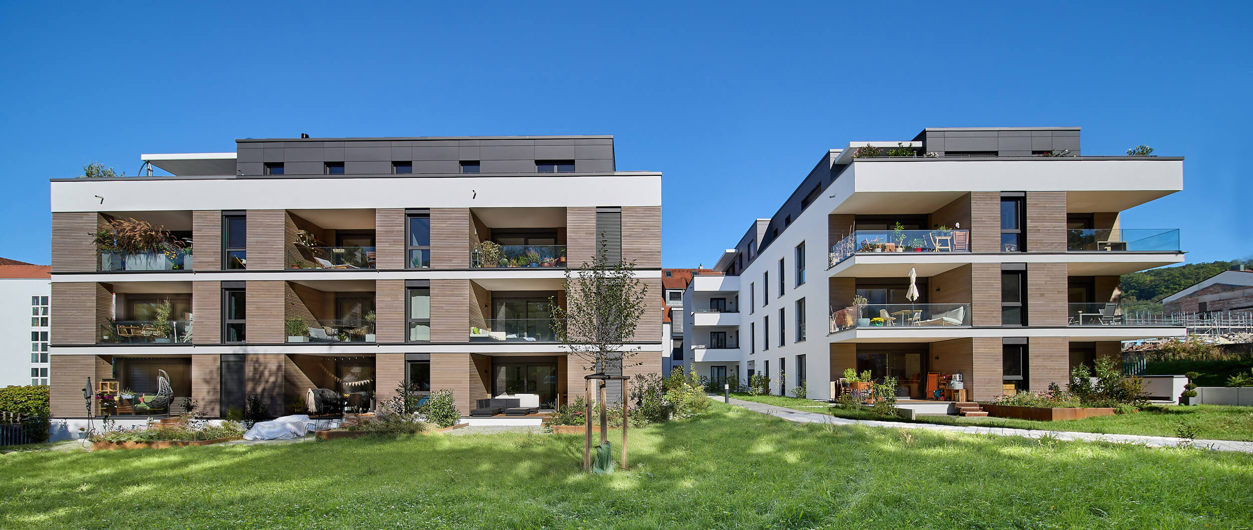 Moderne Wohnanlage mit mehreren Gebäuden, Balkonen und begrünten Außenflächen.